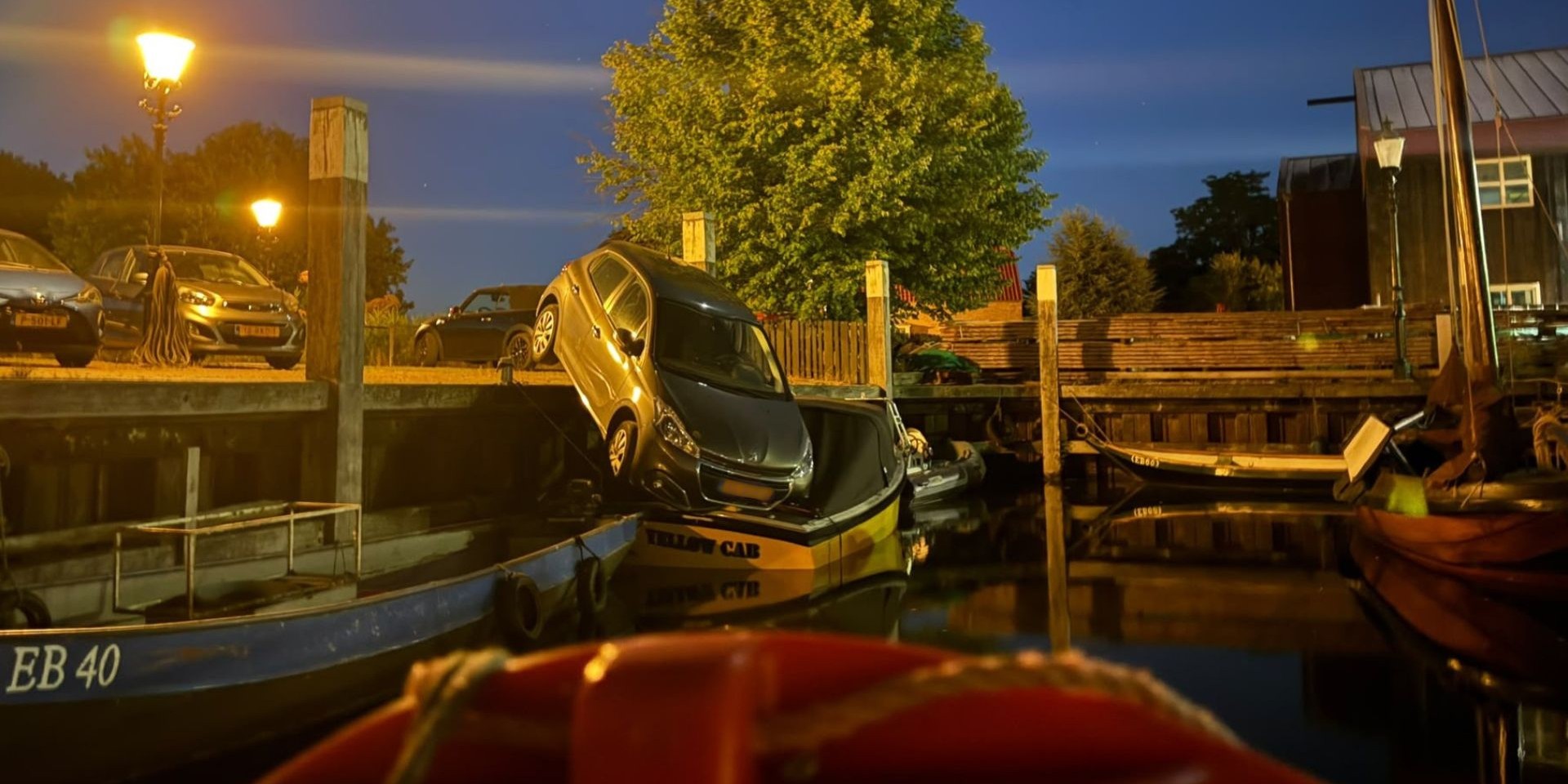 Foto: Een auto rijdt de haven van Elburg in en belandt op boot van Egbert