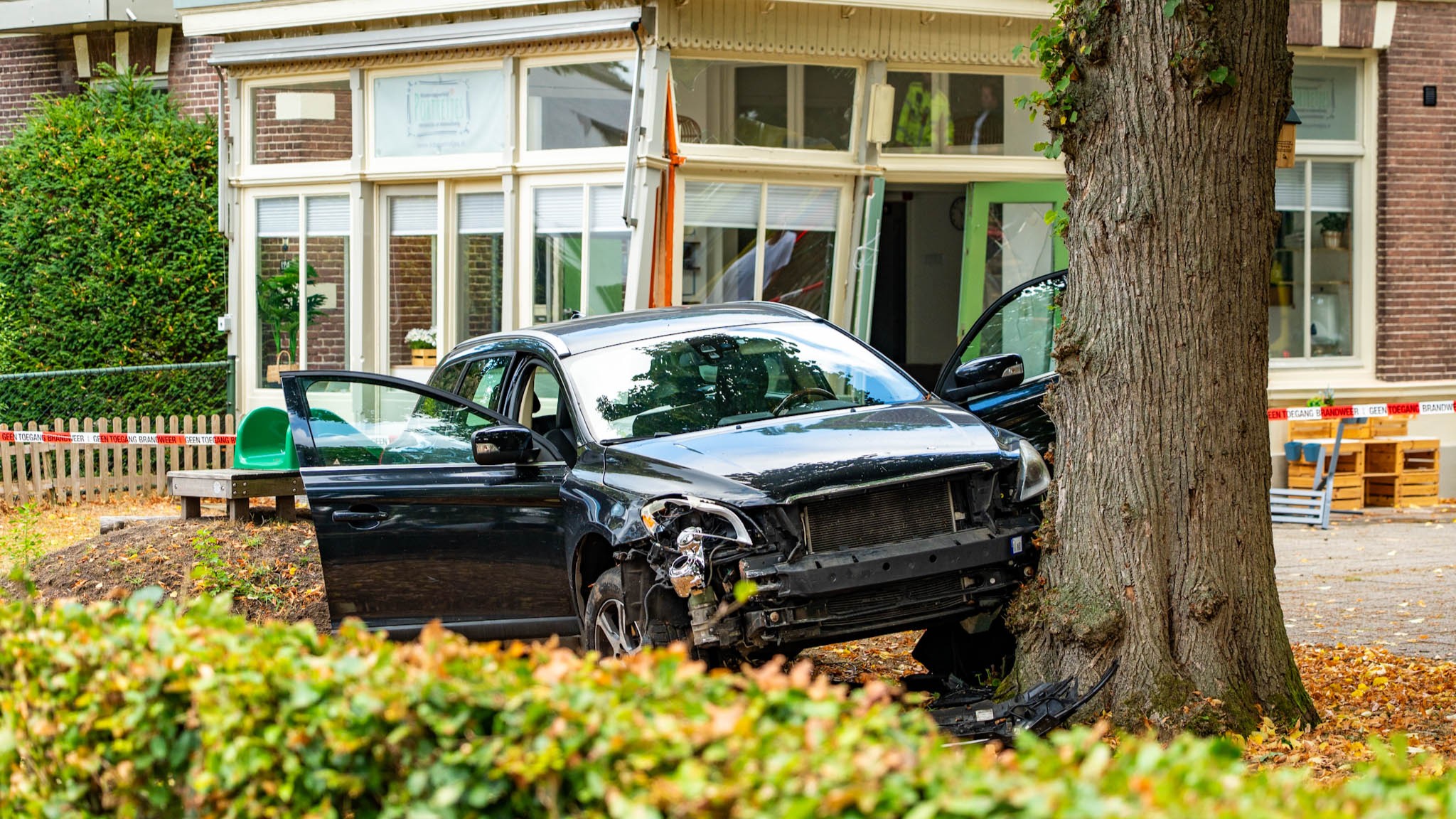 Foto: Auto schiet tuin van kinderdagverblijf in: botst tegen pand en komt tegen boom tot stilstand